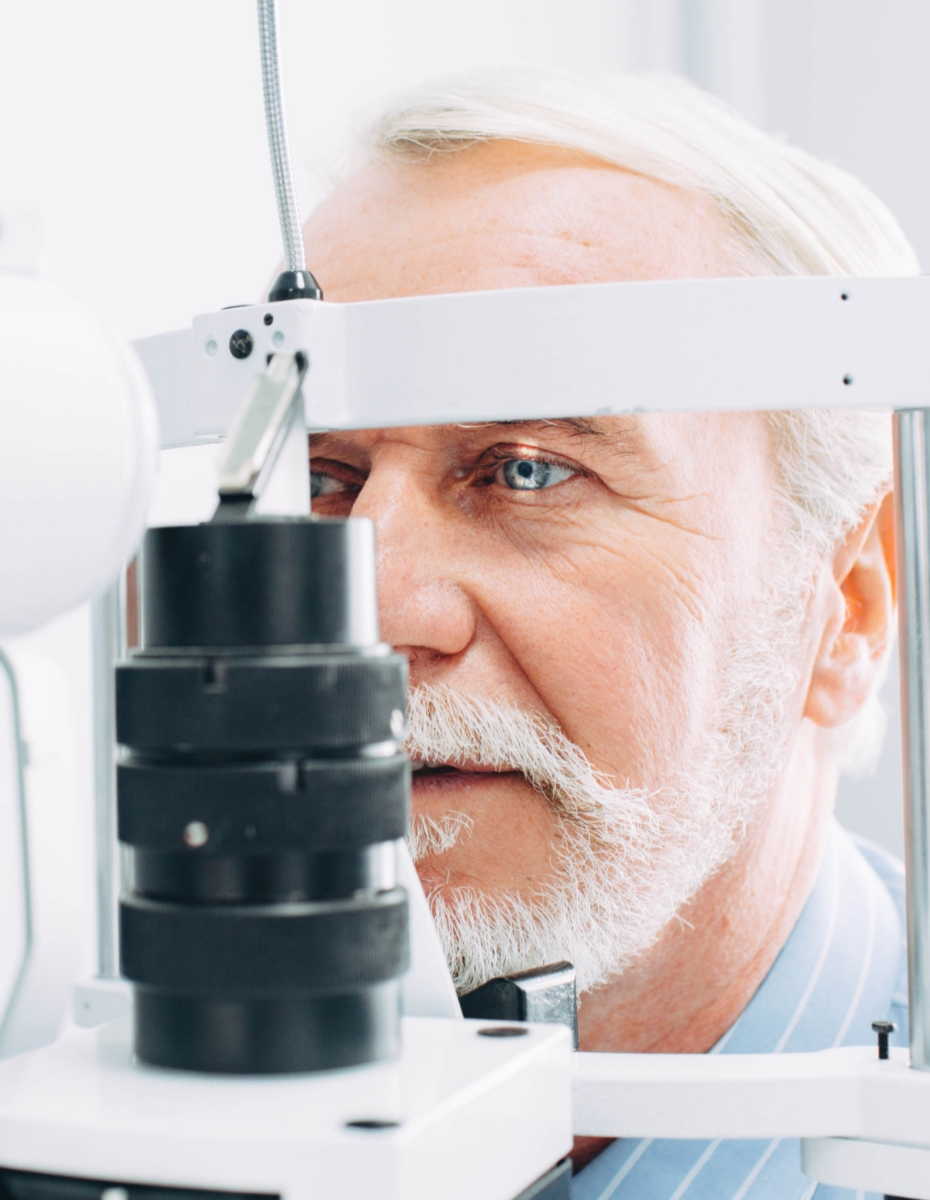 Älterer Mann sitzt vor Spaltlampe.